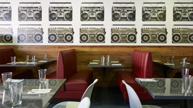 Boombox wallpaper above red booths in the dining room