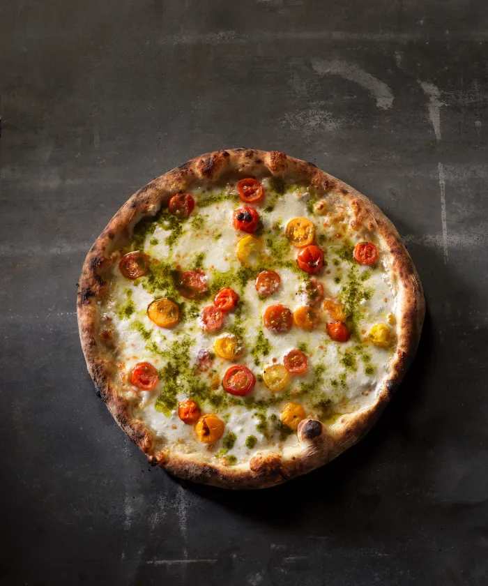 White pizza with pesto and heirloom cherry tomatoes